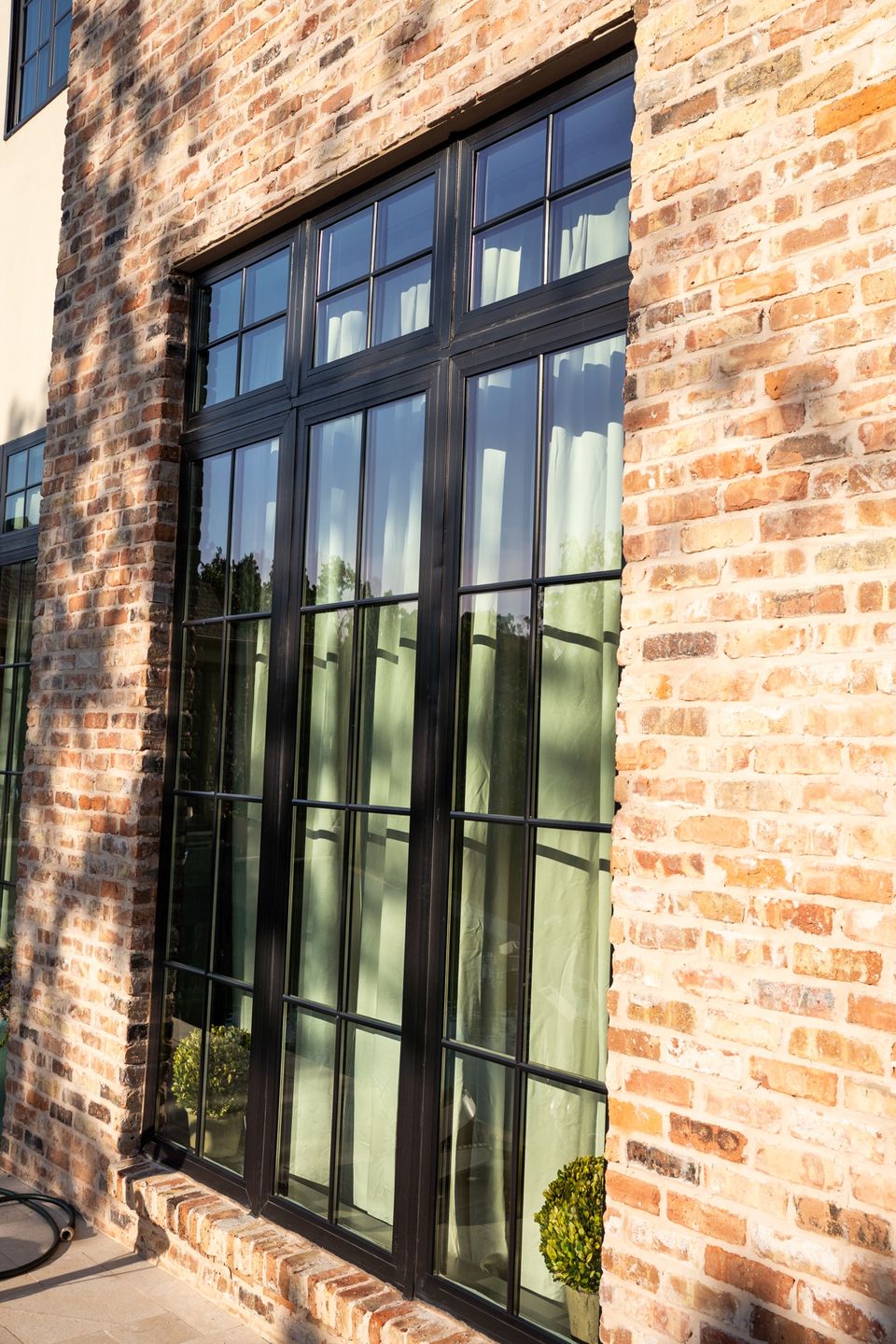 Real Green Window Cleaning exterior service showing tall black-grid windows on a brick home